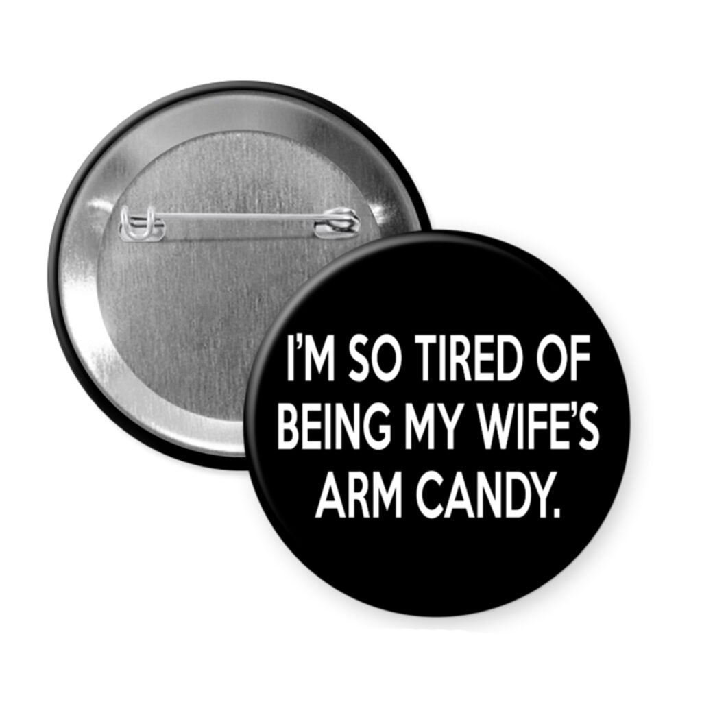 Black pin button that says "I'm so tired of being my wife's arm candy."