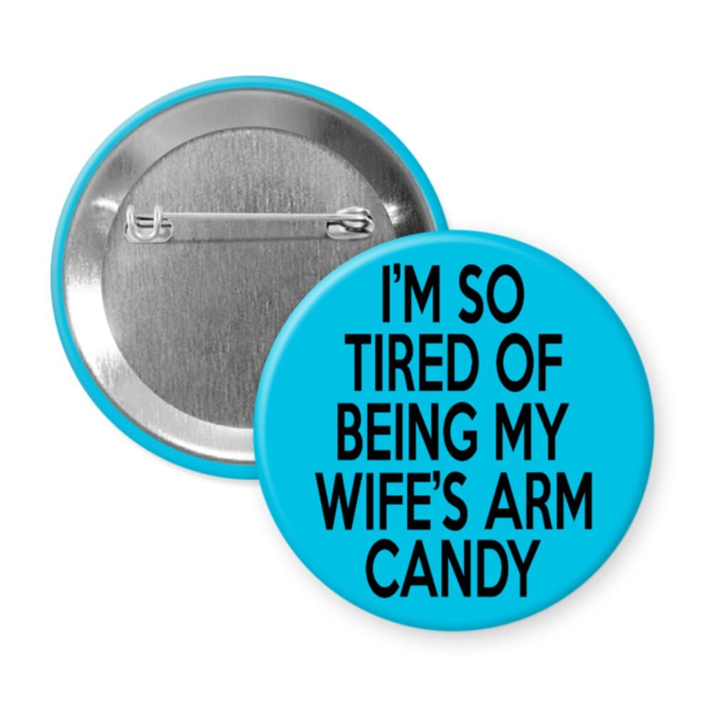 Blue pinback button with text 'I'm so tired of being my wife's arm candy' printed in black.