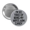 Grey pinback button with text 'I'm so tired of being my wife's arm candy' printed in black.