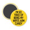 Yellow magnet with text 'I'm so tired of being my wife's arm candy' printed in black.