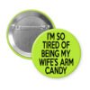 Green pinback button with text 'I'm so tired of being my wife's arm candy' printed in black.