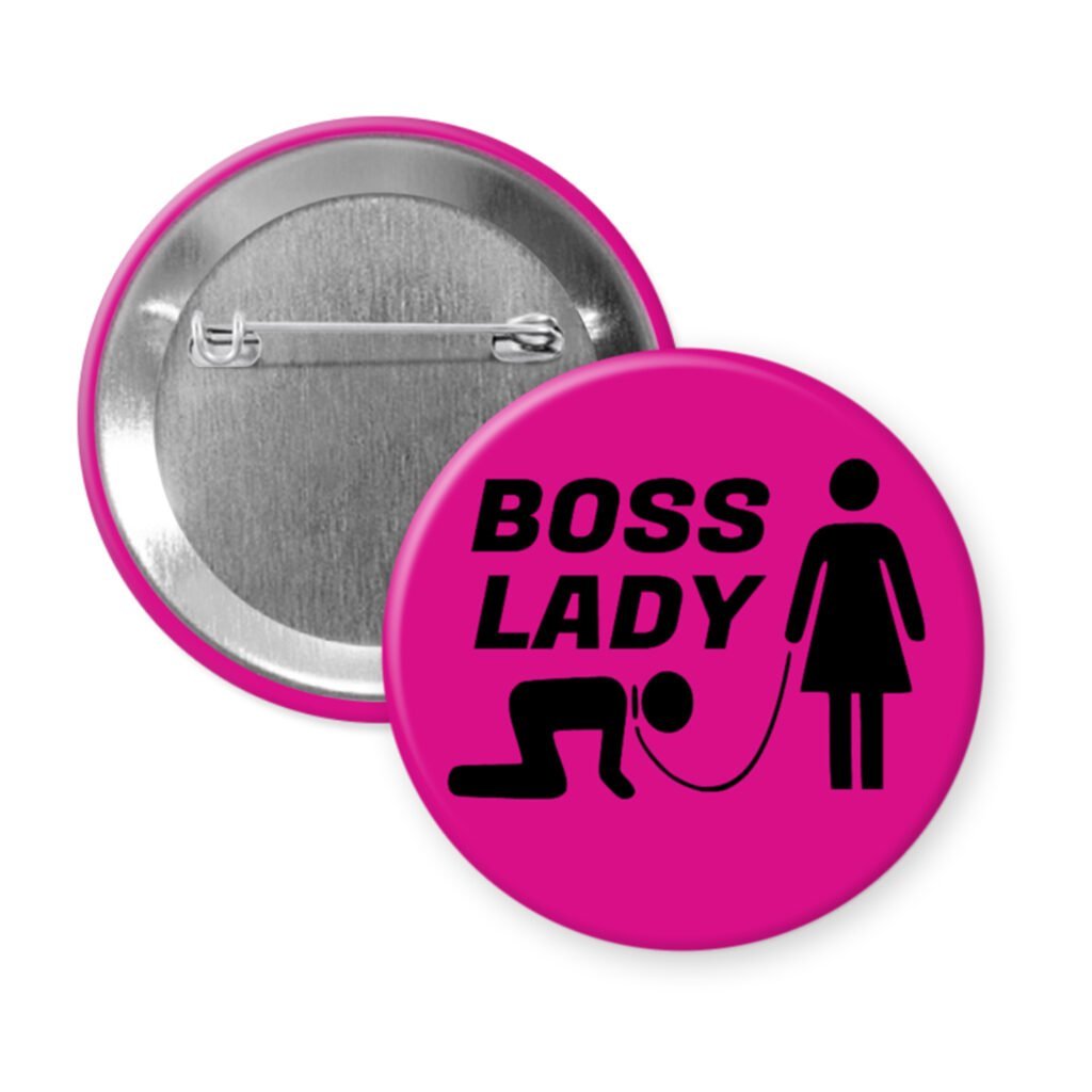 Fuchsia pink pinback button with a graphic of a collared and leashed man on hands and knees, a woman figure holding the leash with the text 'BOSS LADY' printed in black.