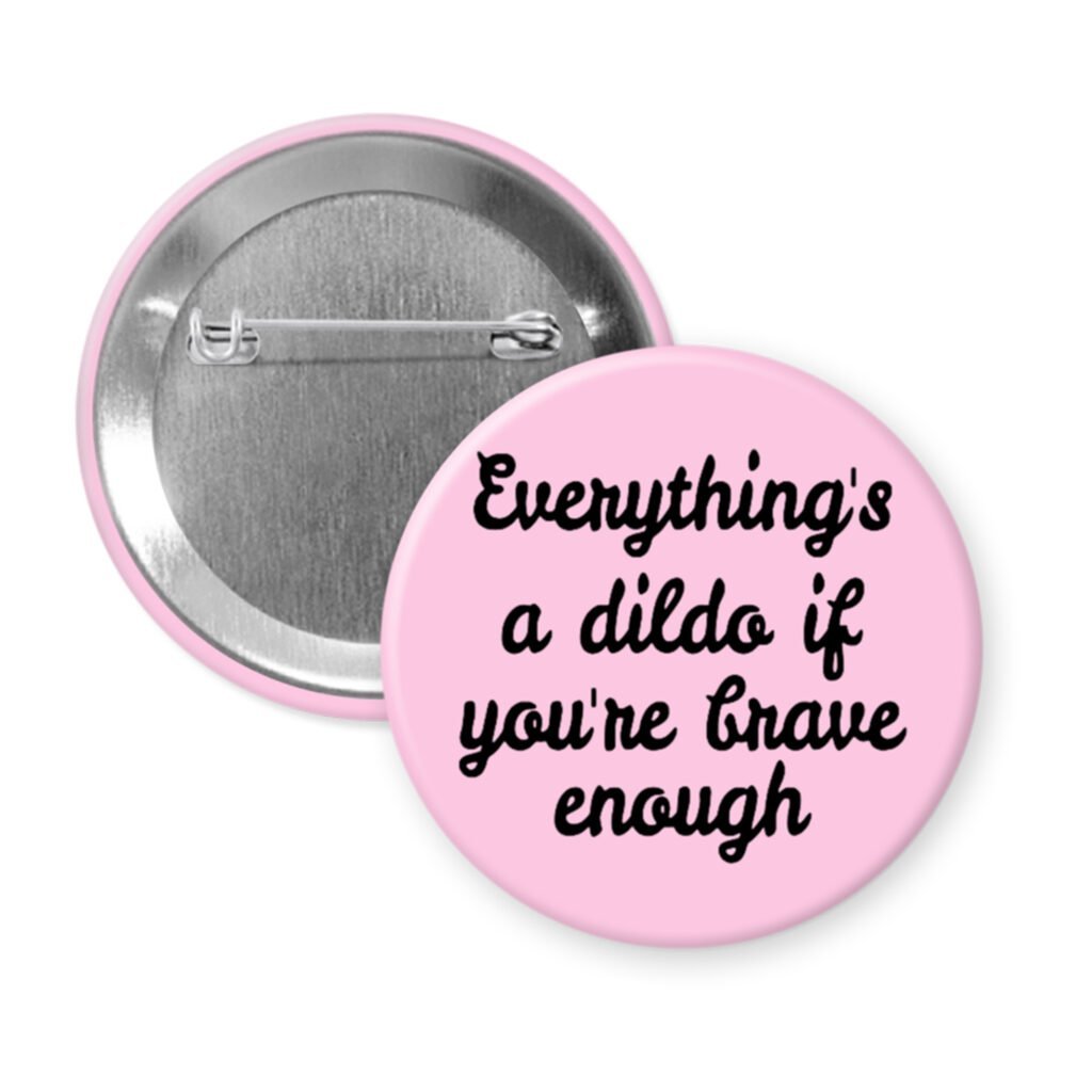 Light pink pinback button with the text 'Everything's a dildo if you're brave enough' printed in black.