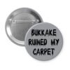 Grey pinback button with the text 'Bukkake ruined my carpet' in black drippy font.