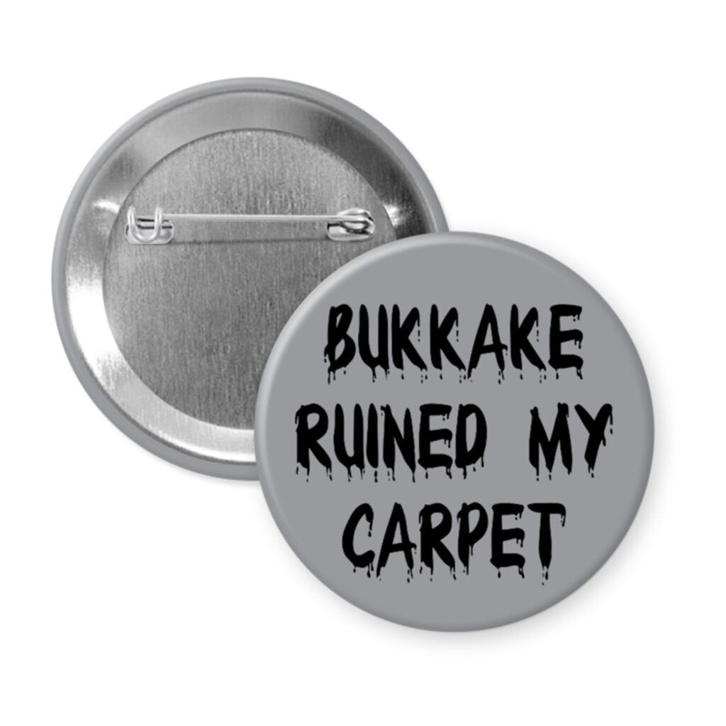 Grey pinback button with the text 'Bukkake ruined my carpet' in black drippy font.