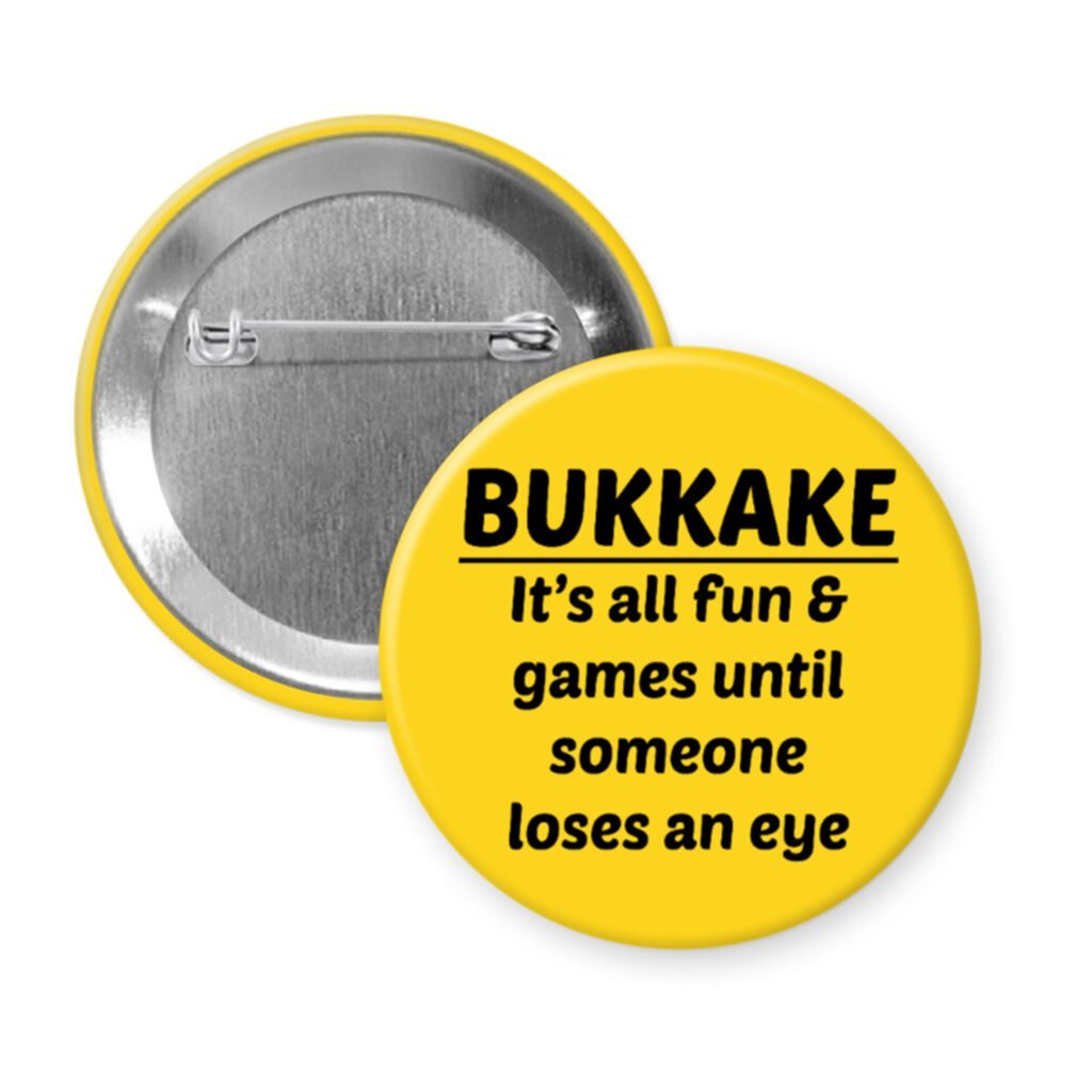 Yellow pinback button with the text 'Bukkake- It's all fun & games until someone loses an eye' printed in black.