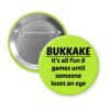 Green pinback button with the text 'Bukkake- It's all fun & games until someone loses an eye' printed in black.
