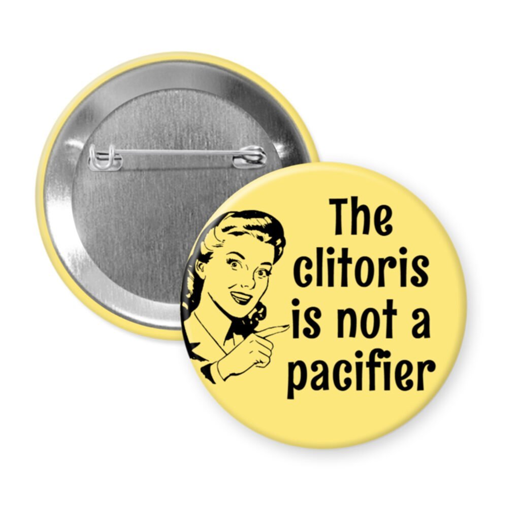 Yellow button with vintage woman graphic and the words "The clitoris is not a pacifier".