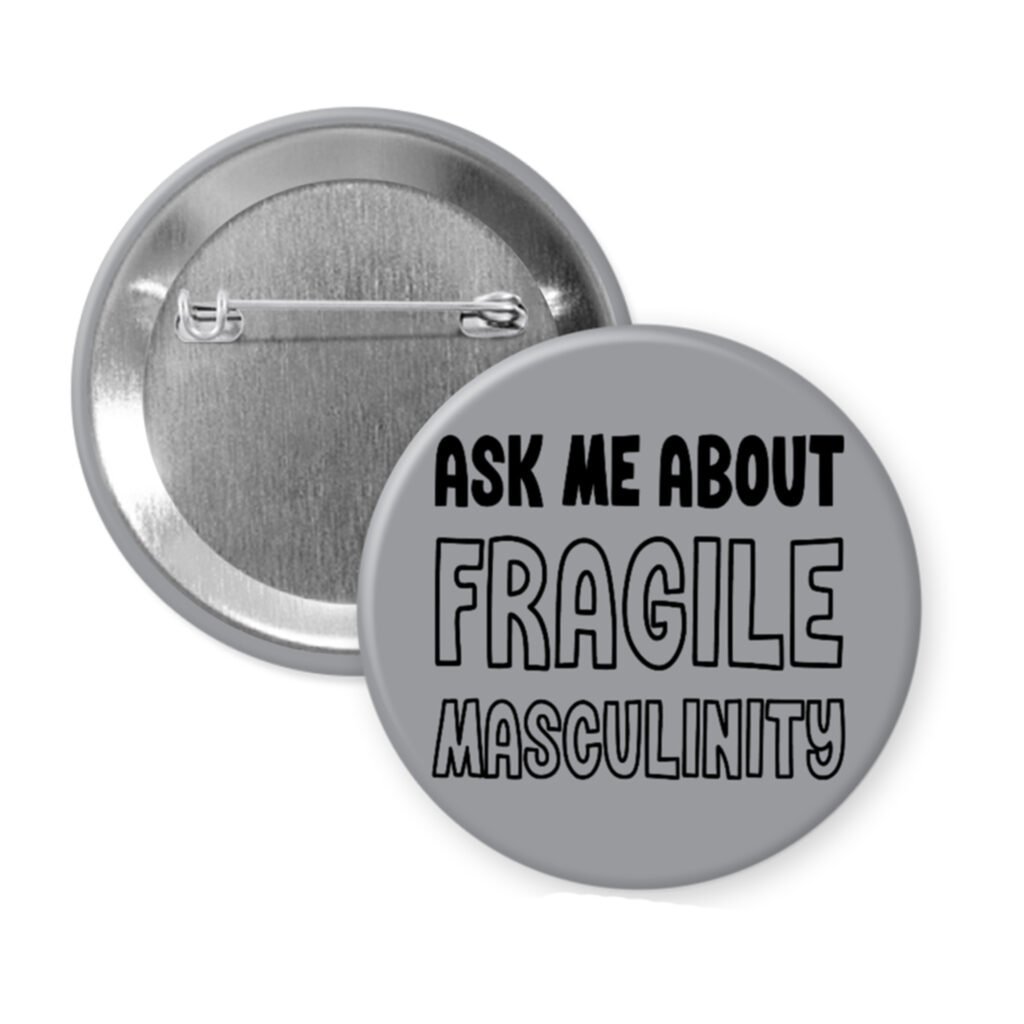Grey pinback button with the text 'Ask me about fragile masculinity' printed in black.