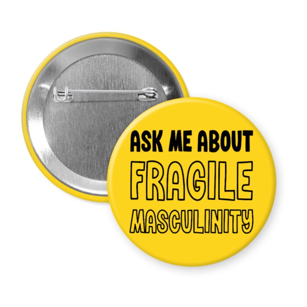 Yellow pinback button with the text 'Ask me about fragile masculinity' printed in black.