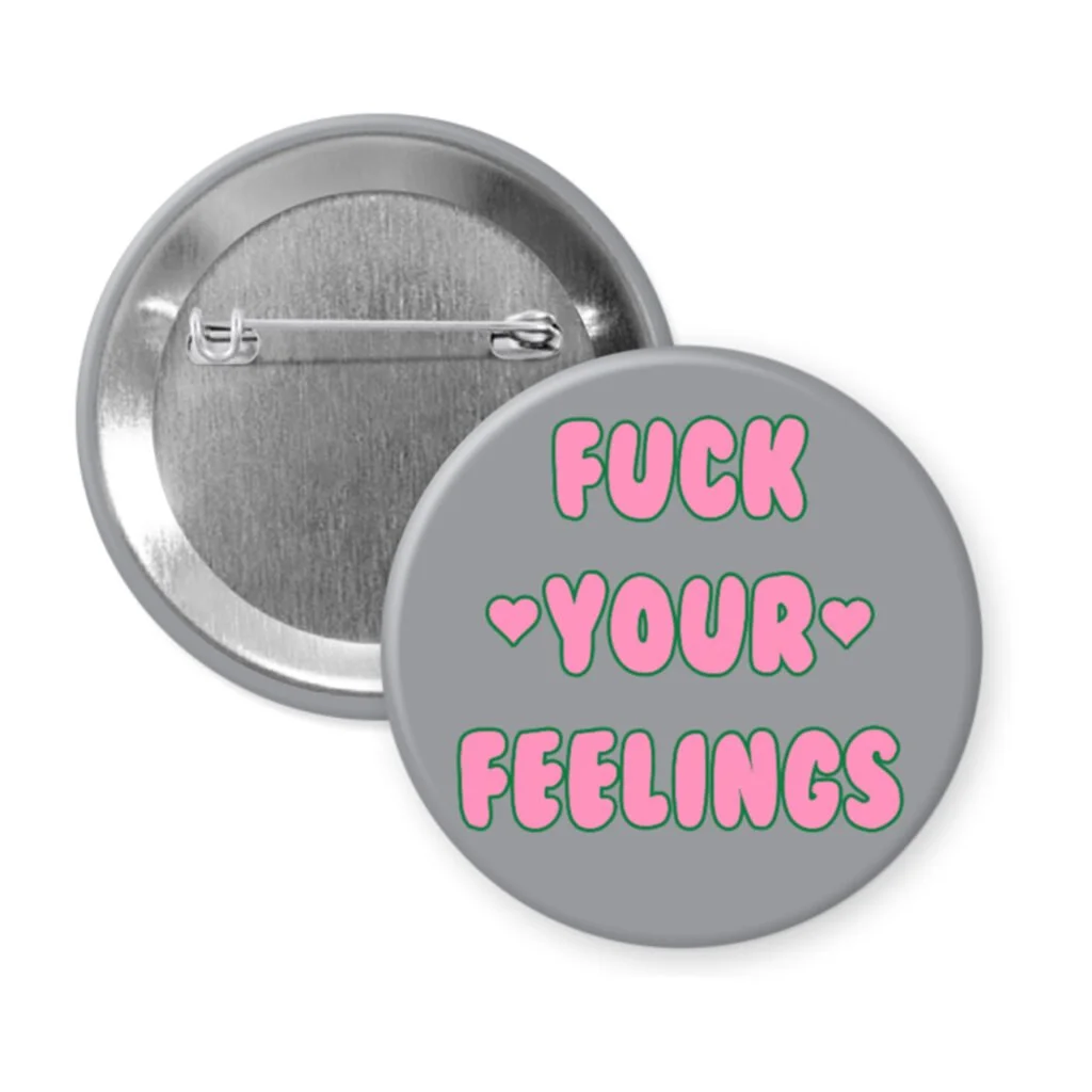 Grey pinback button with the text 'Fuck your feelings' printed in pink.