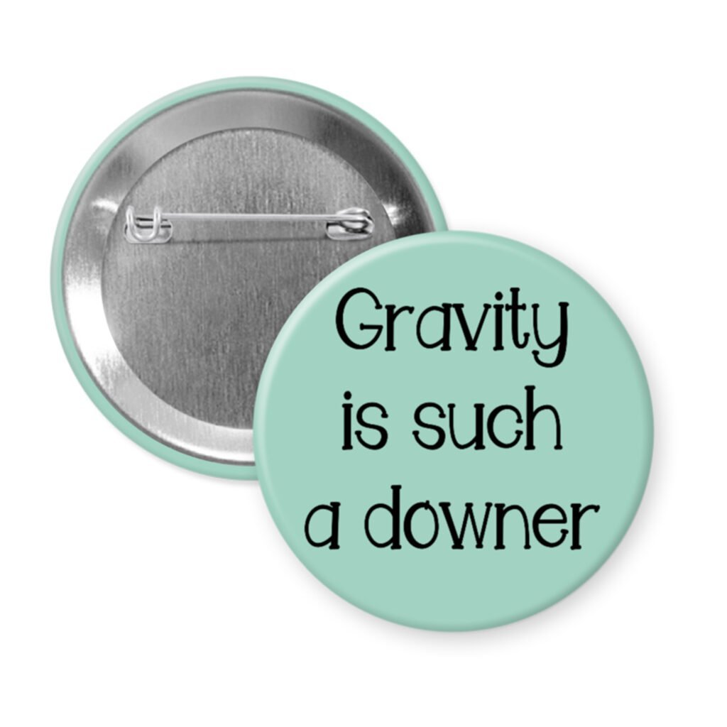 Mint green pinback button with the text 'Gravity is such a downer' printed in black.