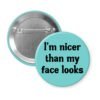 Blue pinback button with the text 'I'm nicer than my face looks' printed in black.