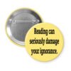 Yellow pinback button with the text 'Reading can seriously damage your ignorance.' printed in black.