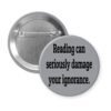 Grey pinback button with the text 'Reading can seriously damage your ignorance.' printed in black.