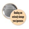 Peach color pinback button with the text 'Reading can seriously damage your ignorance.' printed in black.