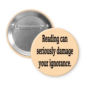 Peach color pinback button with the text 'Reading can seriously damage your ignorance.' printed in black.