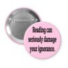 Pink pinback button with the text 'Reading can seriously damage your ignorance.' printed in black.
