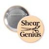 Peach color pinback button with an image of haircutting shears and the text 'Shear Genius' printed in black.