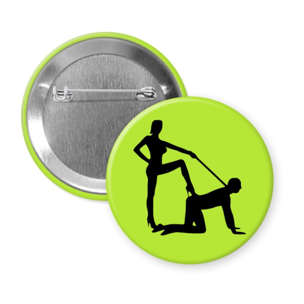 Green pinback button with silhouette image of a man on his hands and knees and a dominatrix holding his leash.