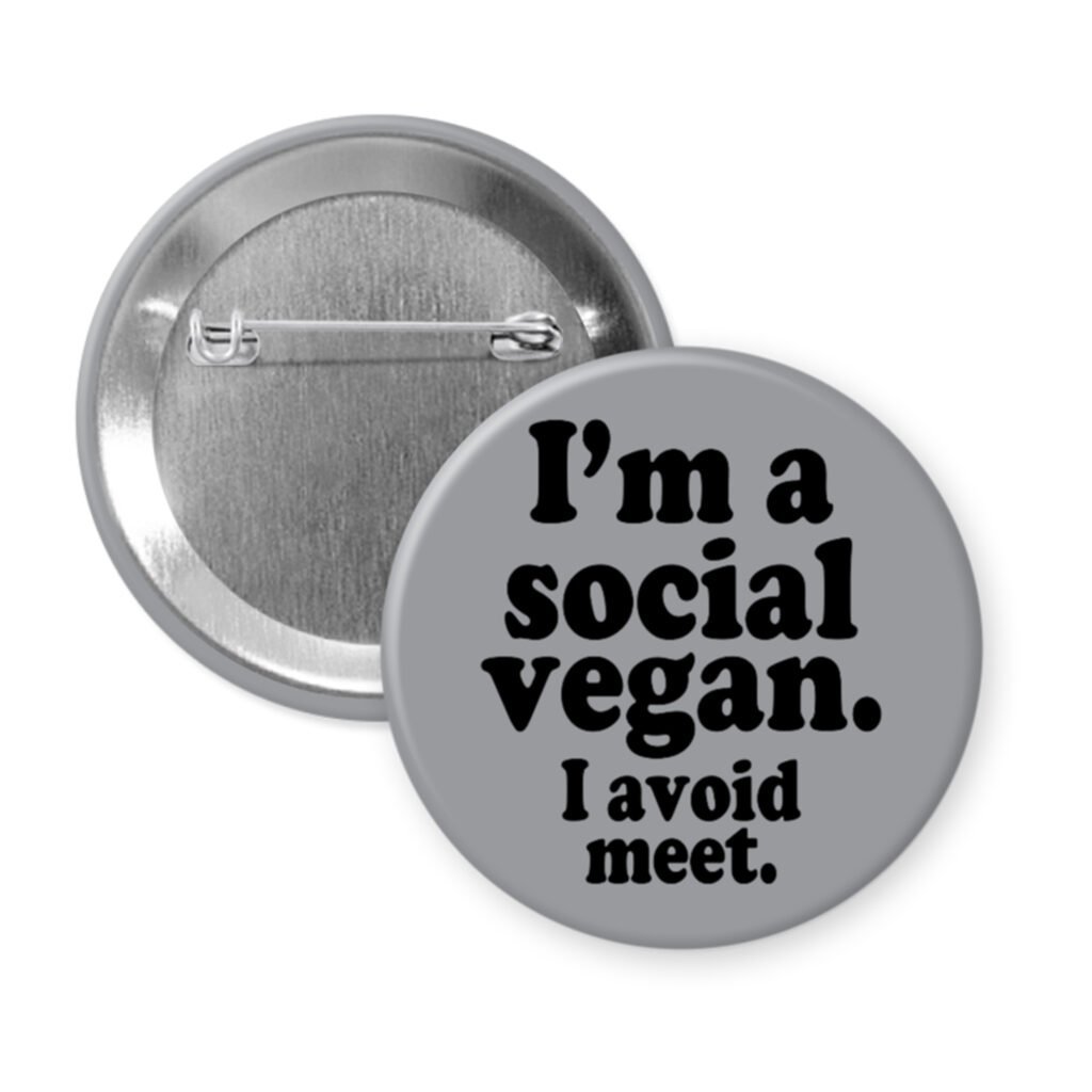 Grey pinback button with the text 'I'm a social vegan. I avoid meet.' printed in black.