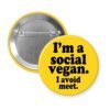 Yellow pinback button with the text 'I'm a social vegan. I avoid meet.' printed in black.