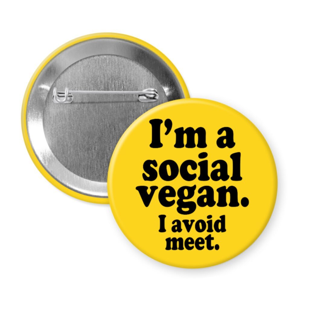 Yellow pinback button with the text 'I'm a social vegan. I avoid meet.' printed in black.