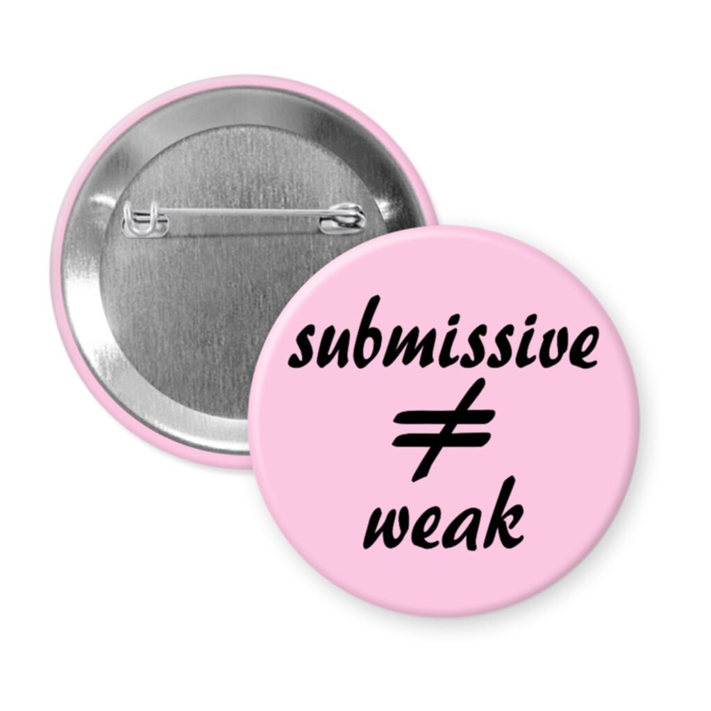 Pink pinback button with the text 'submissive ≠ weak' printed in black.