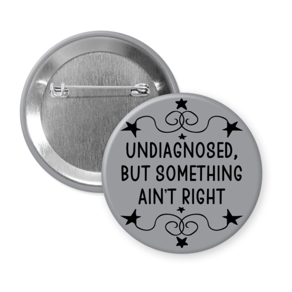 Grey pinback button with the text 'Undiagnosed, but something ain't right' printed in black.
