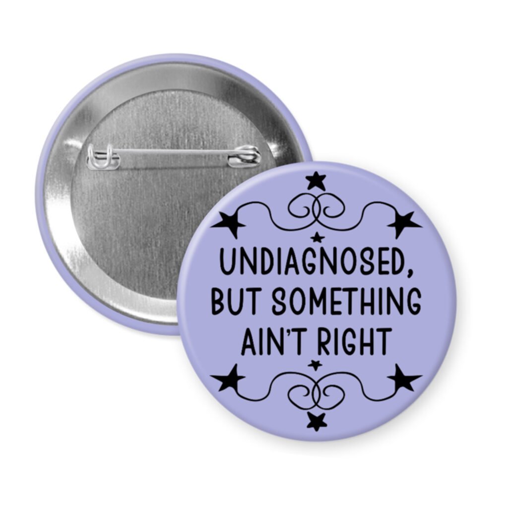 Purple pinback button with the text 'Undiagnosed, but something ain't right' printed in black.