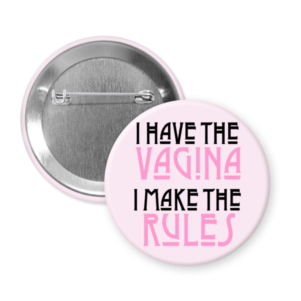 Button badge with text 'I HAVE THE VAGINA I MAKE THE RULES' on a pink background.