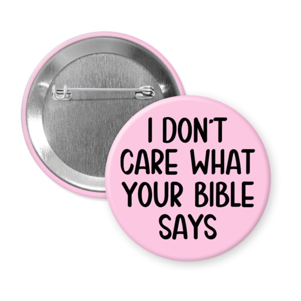 Pink pinback button with the text 'I don't care what your bible says' printed in black.