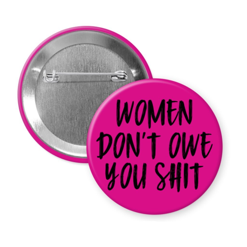 Fuchsia pink pinback button with the text 'Women don't owe you shit' printed in black.