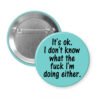 Blue pinback button with the text 'It's ok. I don't know what the fuck I'm doing either.' printed in black.