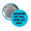 Blue button pin with the text 'Gaslighting isn't real. You're just crazy' in black distressed text.
