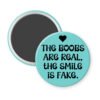 Blue magnet with the text 'The boobs are real, the smile is fake'.
