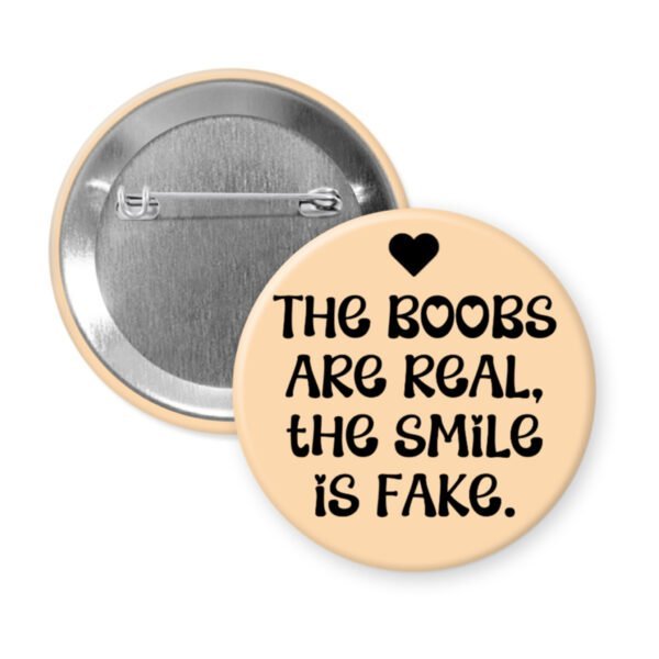Peach button with the text 'The boobs are real, the smile is fake'.