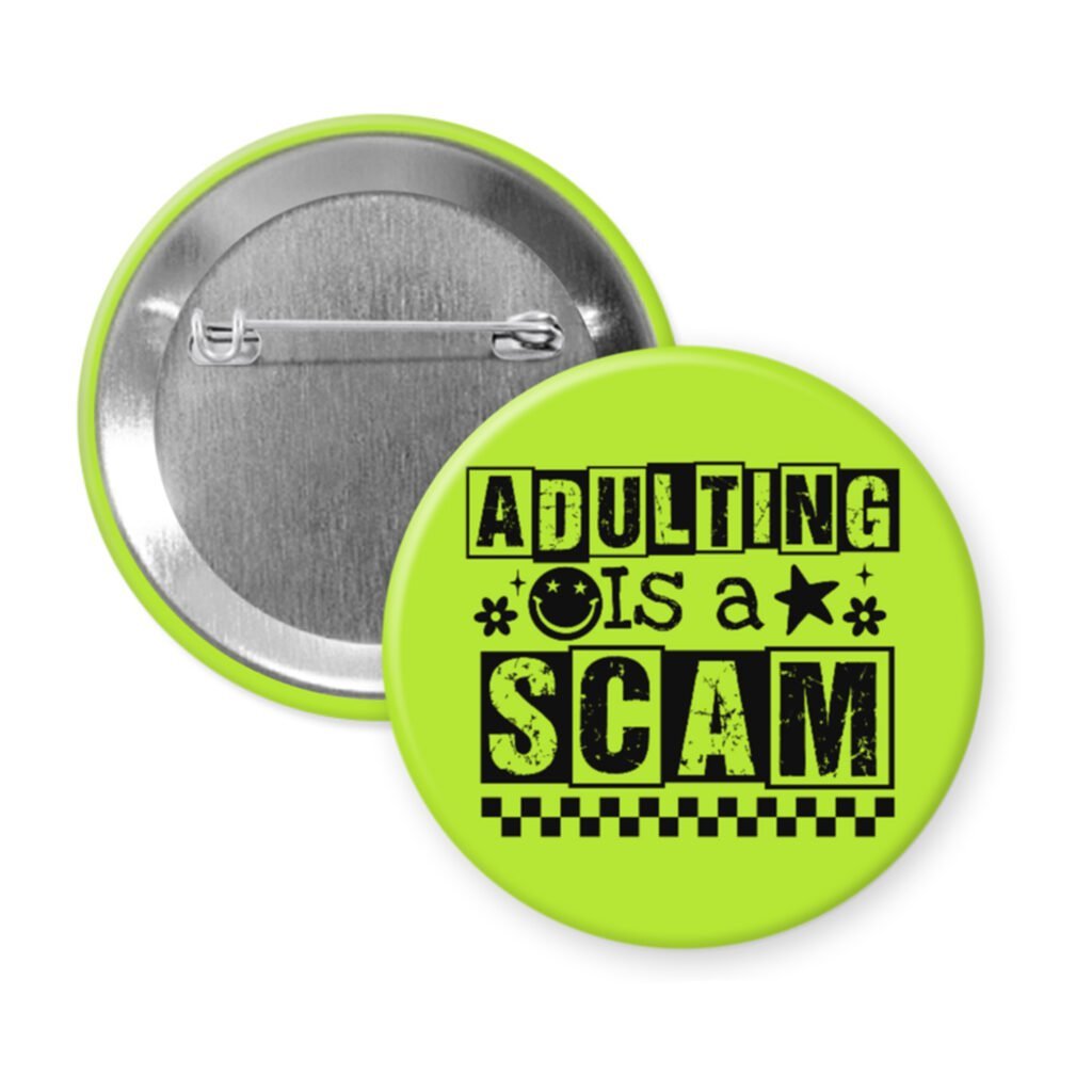 Green pinback button with bold black text reading ‘Adulting is a Scam’ in mixed block and distressed fonts. The design includes a smiley face, star, and flower icons, with a checkerboard stripe along the bottom.