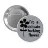 Grey pinback button with image of a flower and the text 'I'm a delicate fucking flower' printed in black.