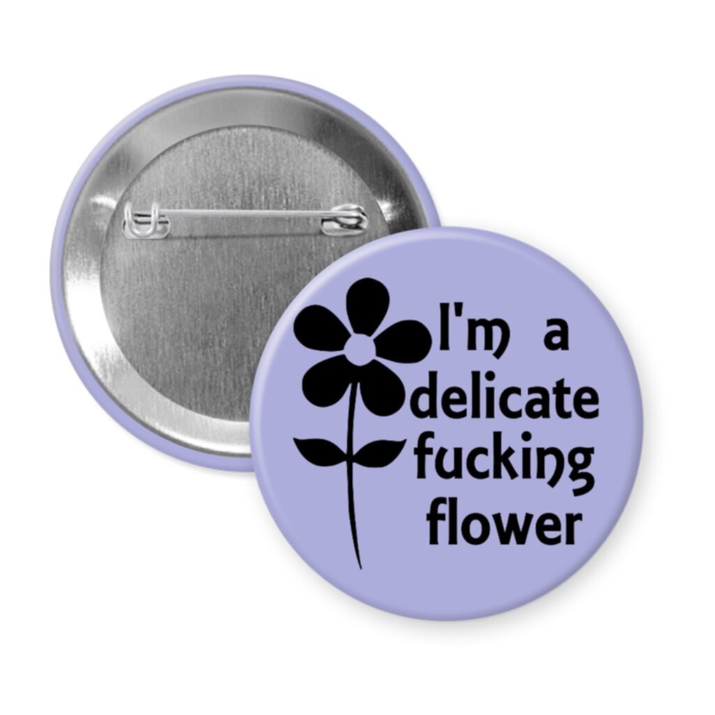Purple pinback button with image of a flower and the text 'I'm a delicate fucking flower' printed in black.
