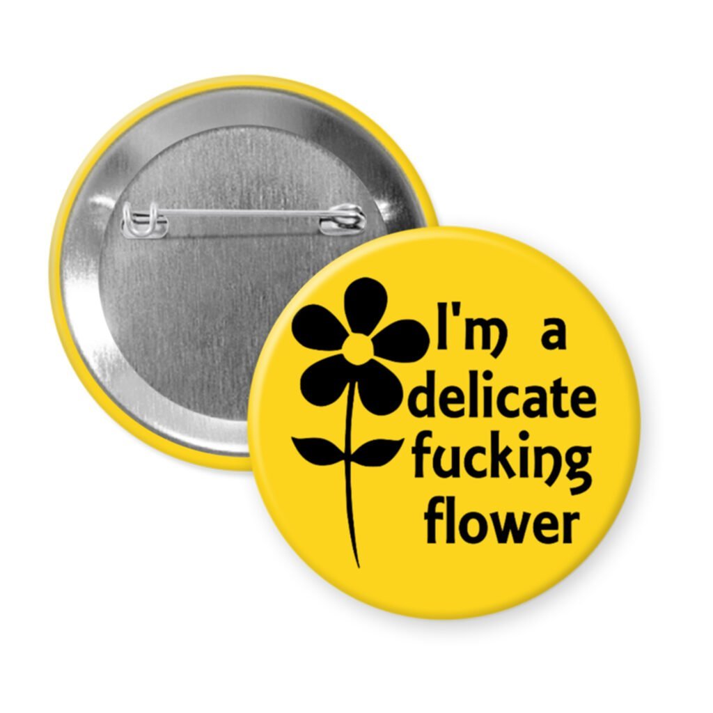 Yellow pinback button with image of a flower and the text 'I'm a delicate fucking flower' printed in black.