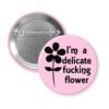 Light pink pinback button with image of a flower and the text 'I'm a delicate fucking flower' printed in black.