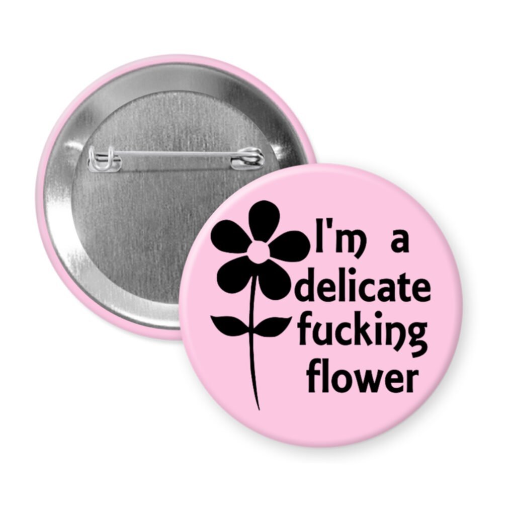 Light pink pinback button with image of a flower and the text 'I'm a delicate fucking flower' printed in black.