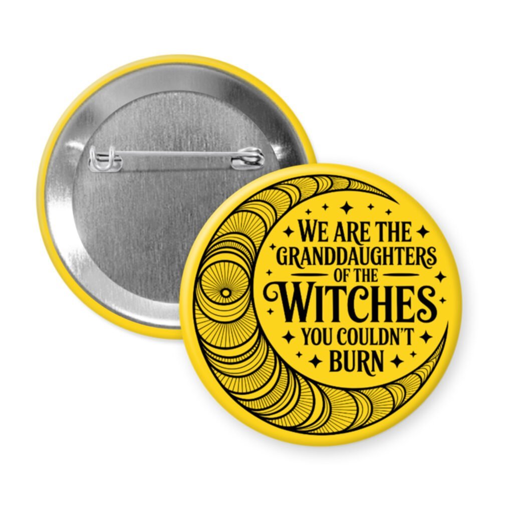 Yellow pinback button with image of a line art moon and the text 'We are the granddaughters of the witches you couldn't burn' printed in black.