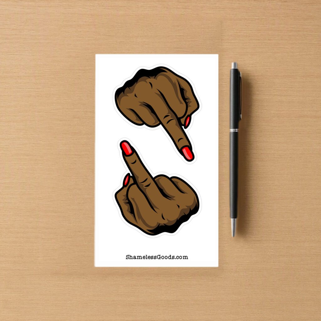 Sticker sheet with two brown hand designs showing middle‑finger gesture and red nails, placed beside a pen on wood surface.