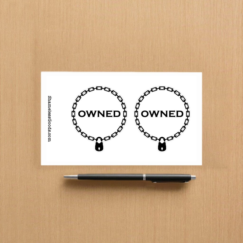 Sticker sheet on a wooden surface beside a black pen, featuring two identical circular chain designs with padlocks at the bottom and the word OWNED in bold black letters inside each circle. Vertical branding text on the left reads ShamelessGoods.com.