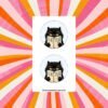 Sticker sheet with two round designs showing a black cat holding an open book that reads Is He Dead Yet in bold letters.